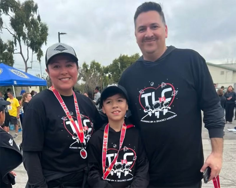 Family wearing TLC 5K shirts and wearing medals at the race event