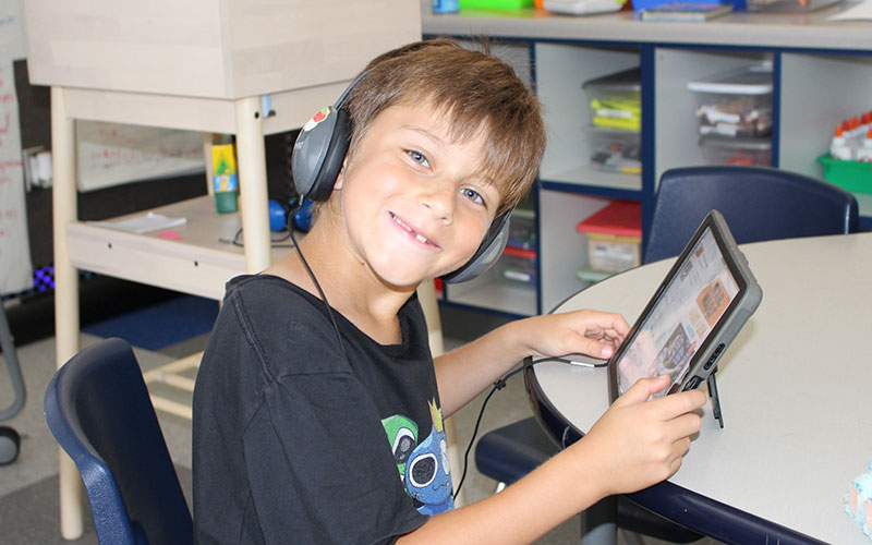 young boy in a classroom with an ipad