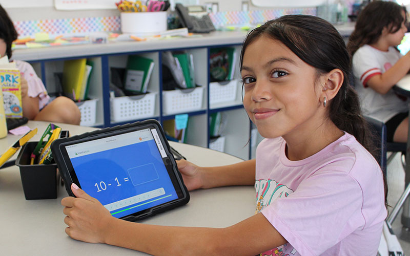 young girl in a classroom with an ipad