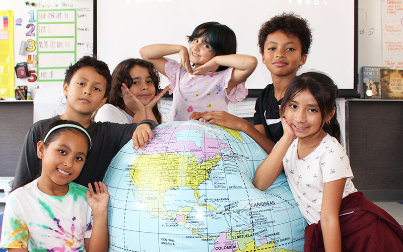group of elementary students interacting with a large globe