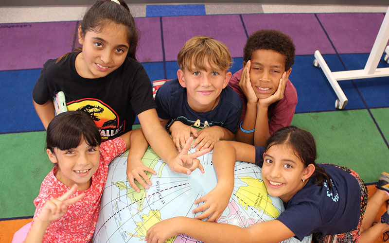 group of elementary students interacting with a large globe