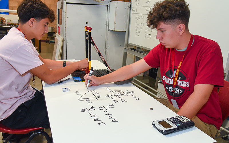 male studenti n front of manufacturing equipment
