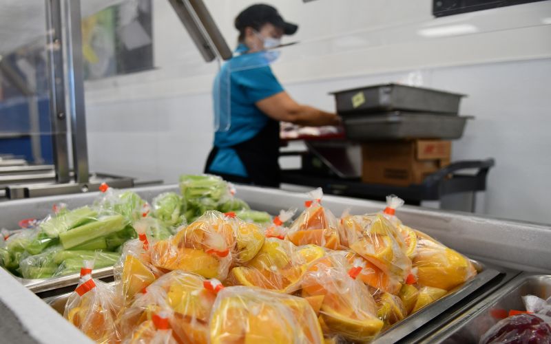 cafeteria worker and closeup of cafeteria food cooking