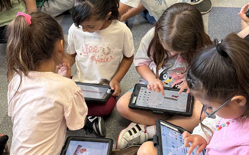 group of young girls focused on ipads