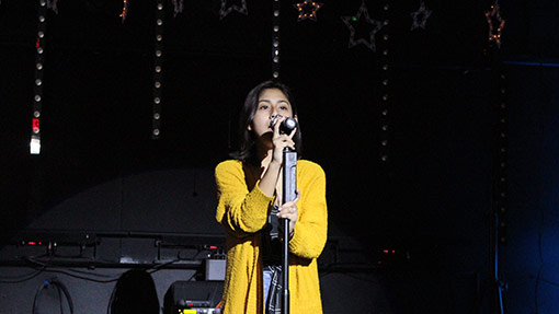 girl singing against a dark stage