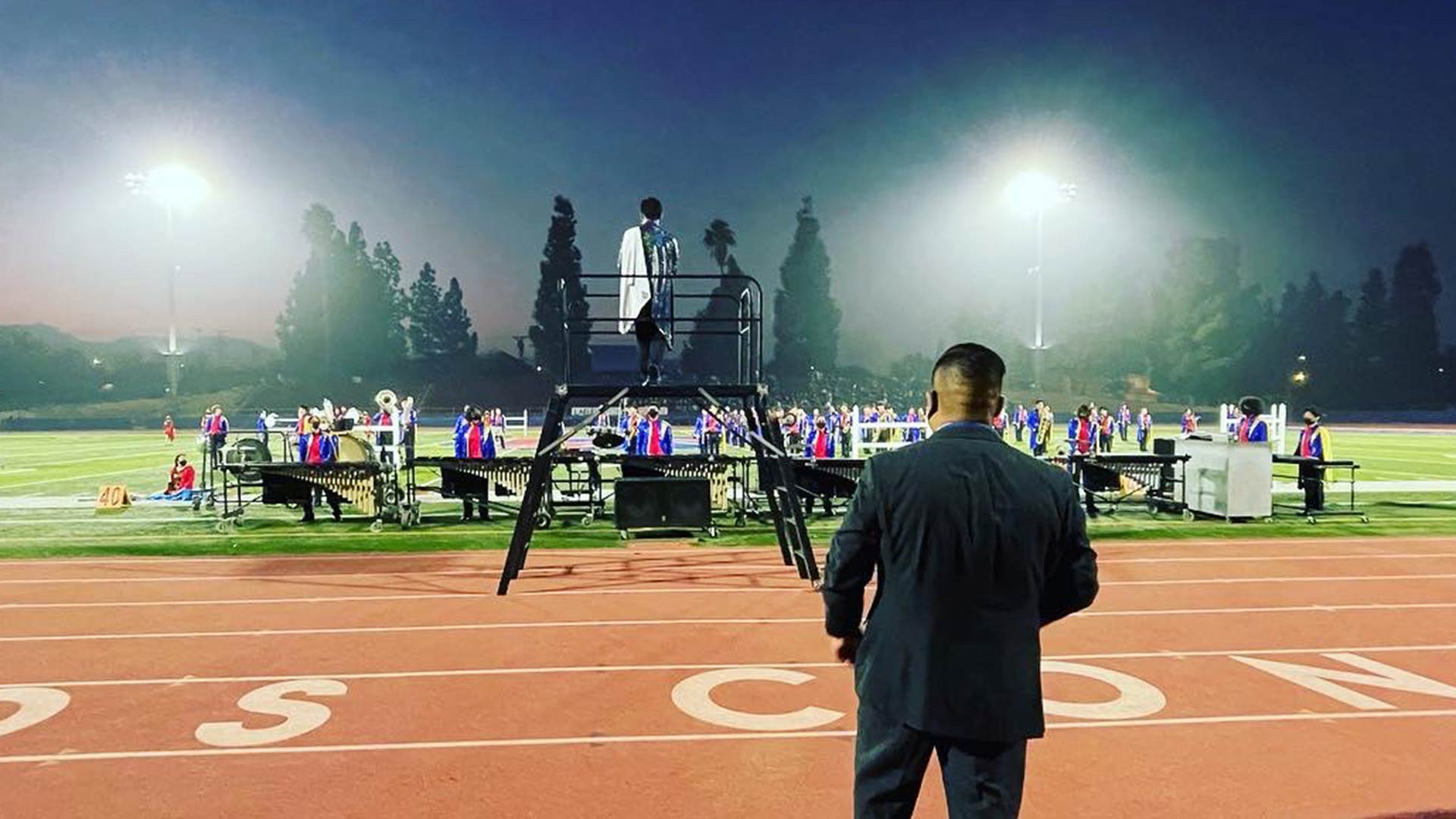 students performing on a backlit playing field