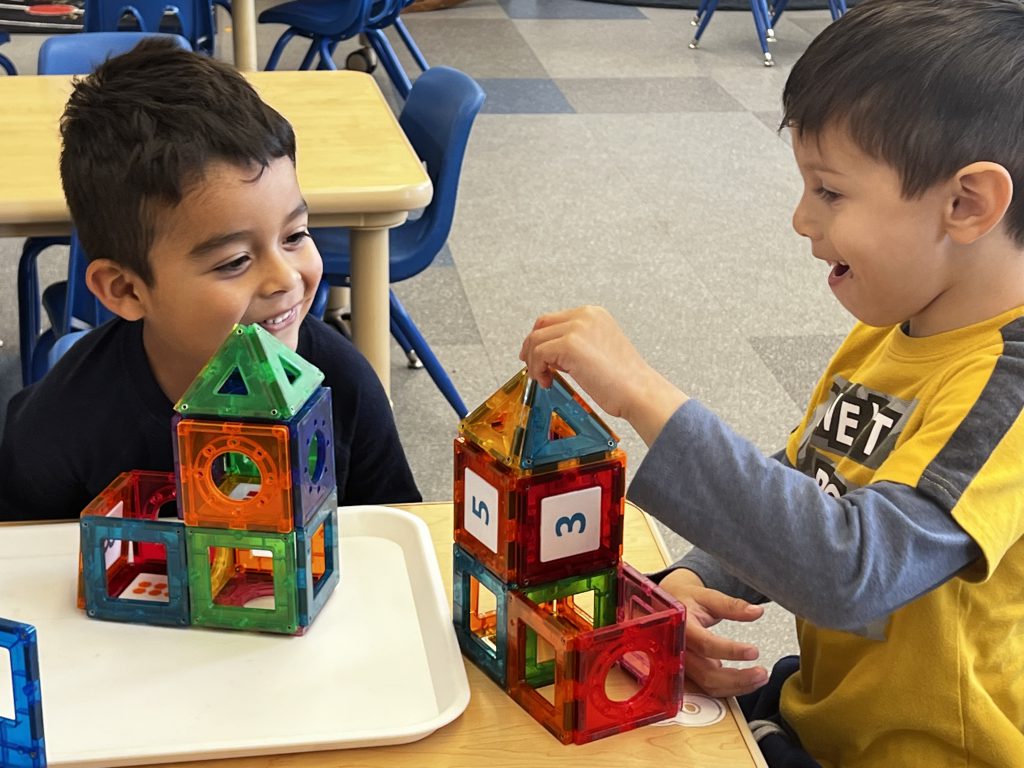 Two students assembling blocks with numbers.