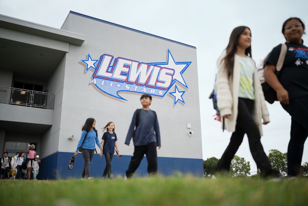 The exterior of e building at Lewis Elementary School, with students walking across the grass.