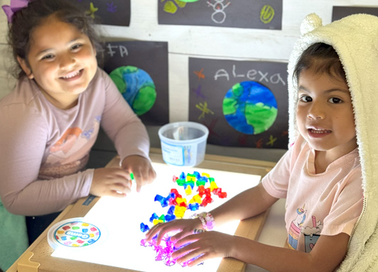 Two young kindergarten students at a light table